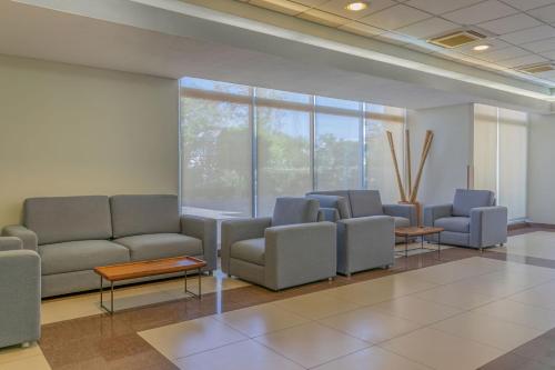 a waiting room with couches and tables and windows at City Express by Marriott Culiacan in Culiacán
