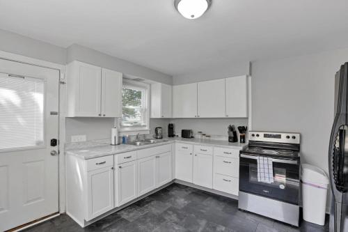 a white kitchen with white cabinets and a stove at The Champion Abode 2 in Columbus