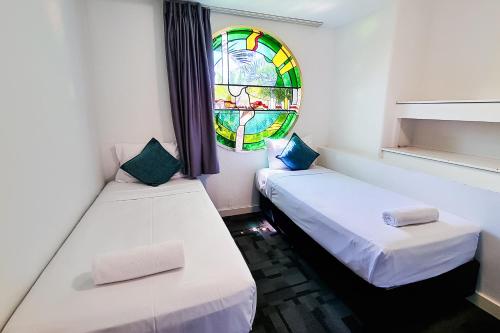 two beds in a room with a stained glass window at Tiki Hotel Apartments Surfers Paradise in Gold Coast