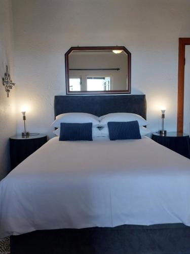 a large white bed with a large mirror above it at The Trailhouse in Bettyʼs Bay
