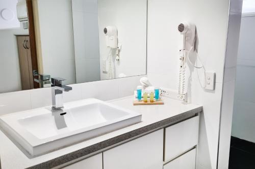 a white bathroom with a sink and a mirror at Tiki Hotel Apartments Surfers Paradise in Gold Coast
