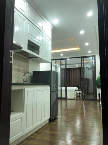 a kitchen with white cabinets and a wooden floor at Khách sạn QUEENIE in Hai Phong