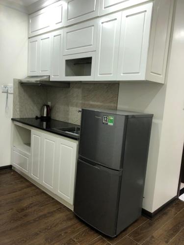 a kitchen with white cabinets and a black refrigerator at Khách sạn QUEENIE in Hai Phong