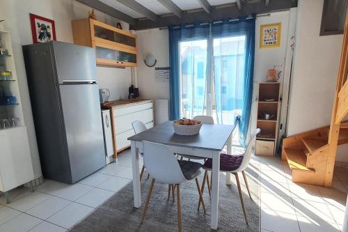 une cuisine avec une table avec des chaises et un réfrigérateur dans l'établissement Appartement Duplex tout confort, à Pierrefiche