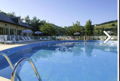 une grande piscine bleue avec chaises et parasols dans l'établissement Appartement Duplex tout confort, à Pierrefiche