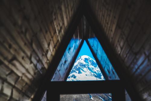 a view of a snow covered mountain through a window at Sanseco Cottage in Stepantsminda