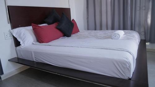 a bed with red and black pillows on it at CommonLens Inn in Entebbe