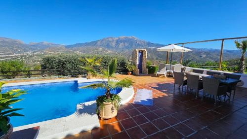 een patio met een zwembad en een tafel en stoelen bij Casita Johanna in Viñuela