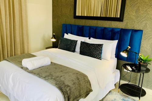 een slaapkamer met een groot bed met een blauw hoofdeinde bij Essence Lifestyle Self-Catering Accommodation - 1523 Hochland Park in Windhoek