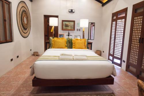 a bedroom with a large white bed with yellow pillows at Nawa Wellness in Calatagan