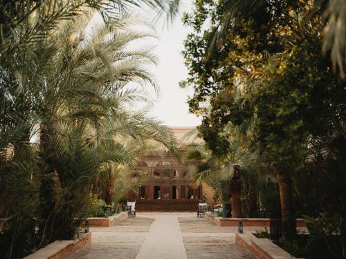 a courtyard with palm trees in front of a building at Al Moudira Hotel in Luxor