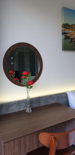 a vase of flowers on a table with a mirror at The Dragon Villa Hoi An in Hoi An