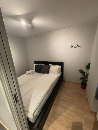 een kleine slaapkamer met een bed met witte lakens bij Amazing apartment by Opera house in Oslo