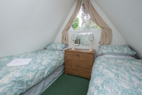 2 camas individuais num quarto no sótão com uma janela. em Chalet Fortyone em Deal