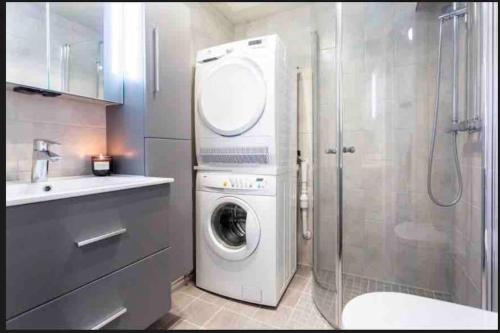 uma casa de banho com uma máquina de lavar roupa e um chuveiro em Nydelig leilighet med sjøutsikt sentralt i byen em Harstad