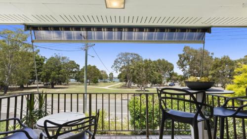 - une terrasse couverte avec des chaises et une table offrant une vue sur un parc dans l'établissement Seaside Serenity Retreat, à Bellara