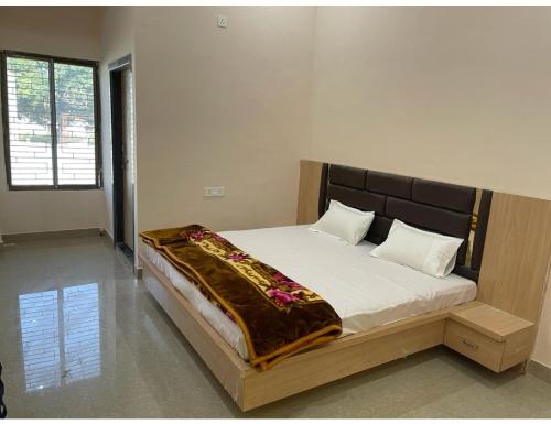 a bedroom with a large bed with white sheets at Uma Hotel, Chitrakoot in Sītāpur Mūāfi