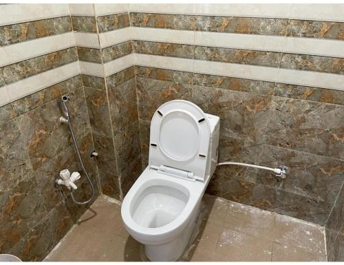 a bathroom with a toilet with the lid up at Uma Hotel, Chitrakoot in Sītāpur Mūāfi