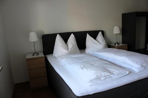 een bed met witte lakens en kussens erop bij Mountain View City Center in Innsbruck