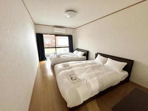 two beds in a small room with a window at 最大10名で泊まれる貸別荘日本橋駅徒歩5分黒門市場に隣接し道頓堀 难波 心斎橋徒歩圏内 in Osaka