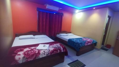 two beds in a room with red and blue lights at DAS HOTEL in Darjeeling