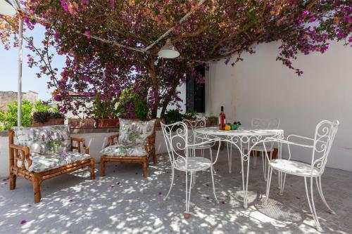 a patio with chairs and a table and a tree at Palazzo Favola Dimora in town centre - Happy Rentals in Corigliano dʼOtranto