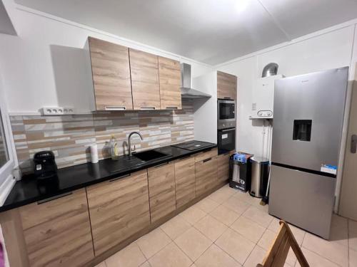 une cuisine avec des armoires en bois et un réfrigérateur en acier inoxydable dans l'établissement Appartement au Duleing House, à Orléans