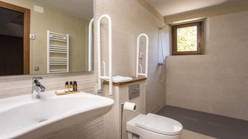 y baño con lavabo, aseo y espejo. en Abbatissa Hotel Restaurant en Sant Joan de les Abadesses