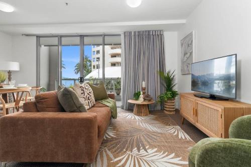 a living room with a couch and a flat screen tv at Lux Retreat at Harbour Light Cairns I Sauna I Pool & prime Location in Cairns