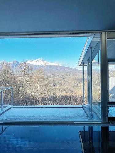 a room with a view of a mountain through a window at Karuizawa Tennku Hotel & Resort in Karuizawa