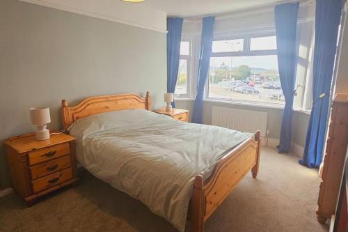 a bedroom with a bed and a window with blue curtains at Avocet View *sleeps 10* in Exmouth