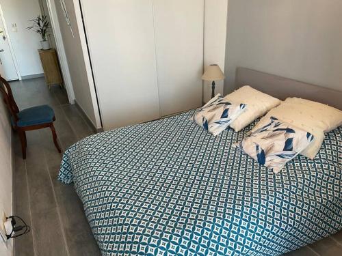 a bed with a blue and white comforter and a chair at Magnifique 2 pièces Juan Les Pins in Antibes