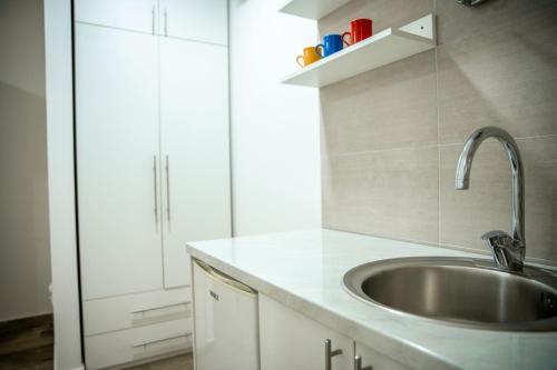 - une cuisine avec un évier et des placards blancs dans l'établissement Jelena Apartmani, à Sombor