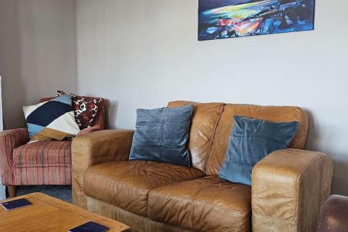 a living room with a brown couch with blue pillows at Avocet View *sleeps 10* in Exmouth