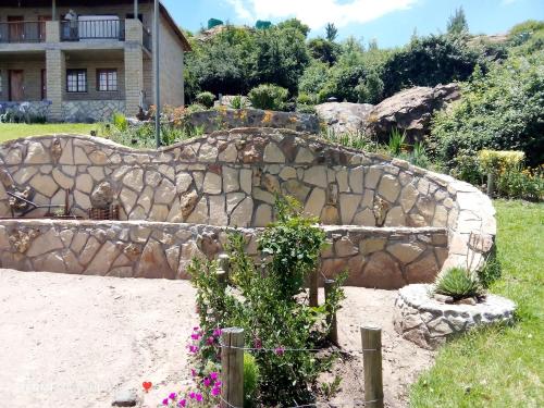a rock retaining wall in a garden with flowers at Monokotsoaing Guest House in Leribe