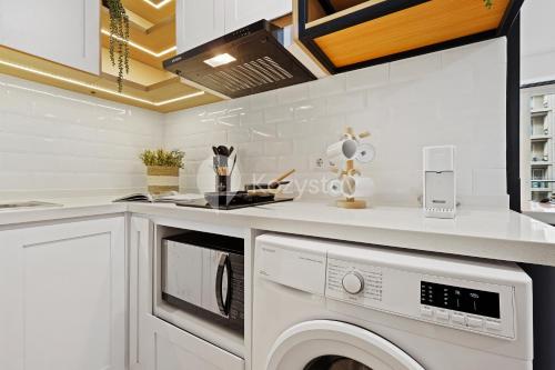a white kitchen with a washer and dryer at Kiara by Kozystay - Paskal in Bandung