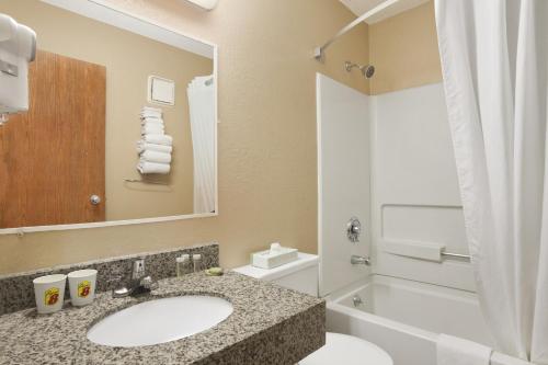 a bathroom with a sink and a toilet and a tub at Super 8 by Wyndham Massena NY in Massena