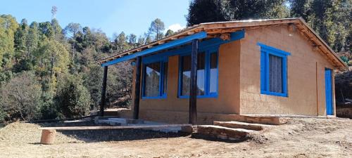 a small house with blue windows on a hill at Idyllic Haven Heritage, Jageshwar in Jageshwar