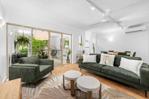 a living room with two green couches and a table at The Nest Cairns - 4 pools BBQ & Resort in Cairns North