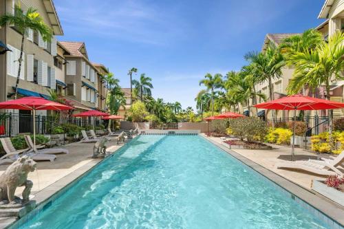 a pool with chairs and umbrellas in a resort at The Nest Cairns - 4 pools BBQ & Resort in Cairns North