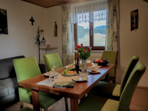 a dining room table with green chairs and a table with food on it at ERLEBNISBAUERNHOF Steinerhof in Kärnten in Liebenfels