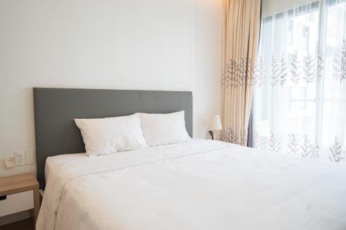 - une chambre avec un lit blanc et une fenêtre dans l'établissement Serviced Apartment at Republic Plaza, à Hô-Chi-Minh-Ville