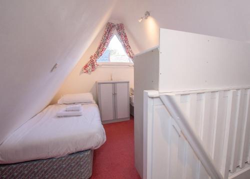 een kleine zolderslaapkamer met een bed en een raam bij Chalet Sixtysix in Deal