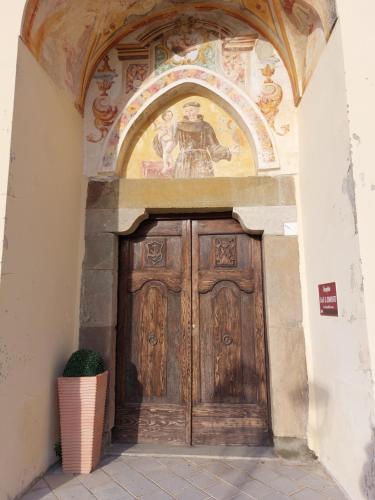 a wooden door in a building with a painting above it at BB Convento Sant Antonio di Laurino in Laurino