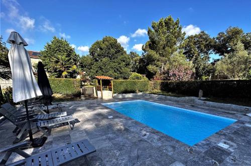 ein Pool mit einem Sonnenschirm, 2 Liegestühlen und einem Sonnenschirm in der Unterkunft Charmante maison de campagne avec piscine in Sartène