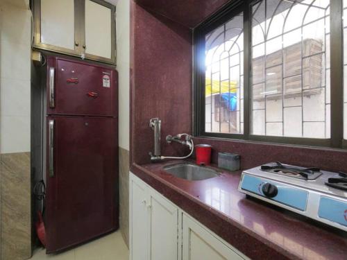 La cuisine est équipée d'un réfrigérateur rouge et d'un évier. dans l'établissement Solace - 1 BHK - Walk away from Carter road, à Mumbai