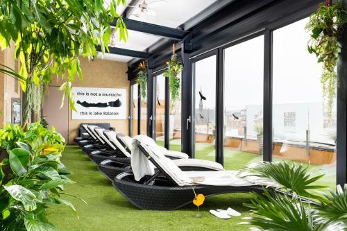 a row of lounge chairs in a room with plants at Bo33 Hotel Family & Suites in Budapest