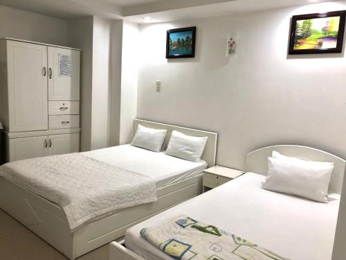 two beds in a small room with white walls at Seven Stars Hotel in Ho Chi Minh City