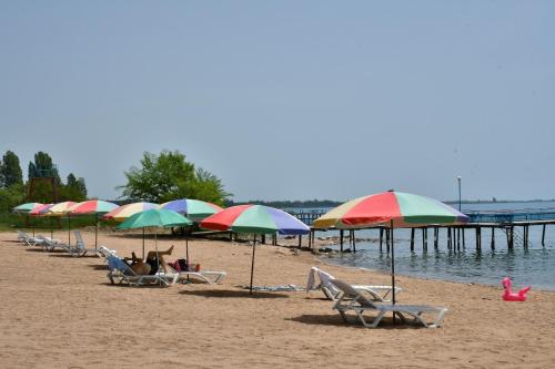 eine Gruppe Liegestühle und Sonnenschirme am Strand in der Unterkunft пансионат Нептун in Korumdy