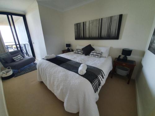 a bedroom with a large bed and a chair at Serenity by the Sea in Rockingham